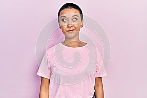 Beautiful hispanic woman with short hair wearing casual pink t shirt smiling looking to the side and staring away thinking