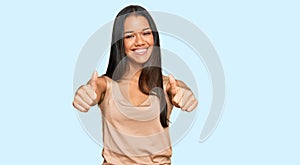 Beautiful hispanic woman wearing casual clothes approving doing positive gesture with hand, thumbs up smiling and happy for
