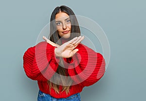 Beautiful hispanic woman wearing casual clothes rejection expression crossing arms and palms doing negative sign, angry face