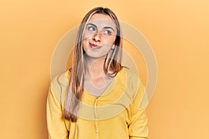 Beautiful hispanic woman wearing casual yellow sweater smiling looking to the side and staring away thinking