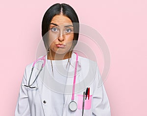Beautiful hispanic woman wearing doctor uniform and stethoscope depressed and worry for distress, crying angry and afraid