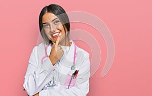 Beautiful hispanic woman wearing doctor uniform and stethoscope looking confident at the camera smiling with crossed arms and hand