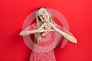 Beautiful hispanic woman wearing summer dress smiling in love doing heart symbol shape with hands