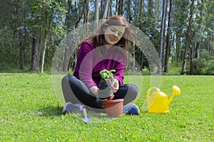 Beautiful Hispanic young woman placing a small plant inside a pot in her home garden