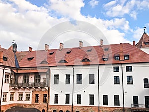 Beautiful historical medieval European low-rise buildings with a red tile roof gable and rectangular windows with bars