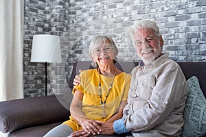 Beautiful hoary good-looking mature spouses relaxing together on comfy couch at modern home smiling staring at camera feel