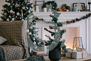 Beautiful holiday decorated room with Christmas tree, fireplace and armchair with blanket