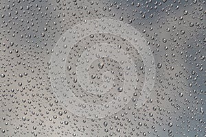 A horizontal texture of water droplets is on the glass and on a background of blue sky