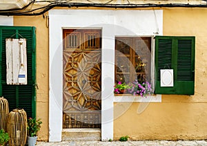 Beautiful house facade with an impressive wooden door and window shutters with blank signs for decoration in mediterranean summer