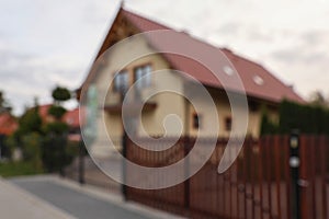 Beautiful house near fence outdoors, blurred view. Real estate for rent