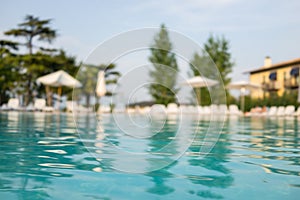 Beautiful house, swimming pool view from the veranda, summer day (Focus on pool water)..