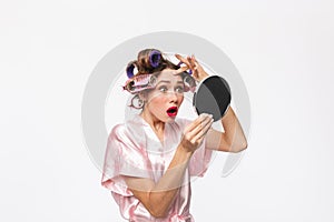 Beautiful housewife with curlers in hair wearing robe