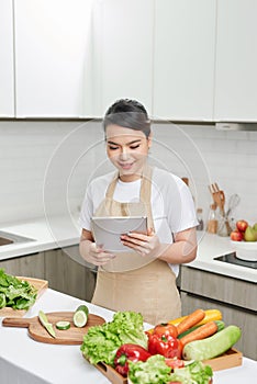 Beautiful housewife lady hold digital tablet searching recipe internet lecture master class cook delicious family dinner