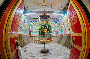 Beautiful huge bhuddhist prayer wheel in an ornately decorated room shot with a fisheye lens