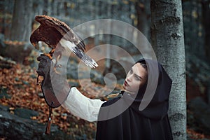 Beautiful huntress with hawk in a forest