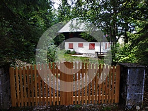 Beautiful hut with red window blinds behind fence near Le Markstein