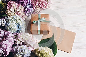 Beautiful hydrangea flowers, gift box and paper greeting card on rustic white wood, with space for text. Happy mothers day