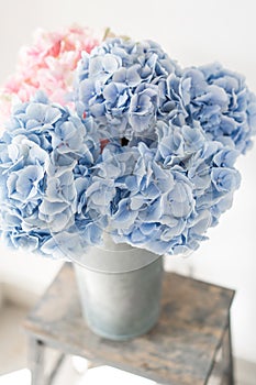 Beautiful hydrangea flowers in a vase on a table . Bouquet of light blue. Decoration of home. Wallpaper and background.