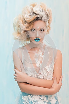 Beautiful ice queen with blue lips and hairstyle with snow in hair