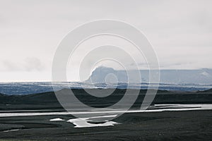 beautiful icelandic landscape with black volcanic sand in snow and rocky mountains