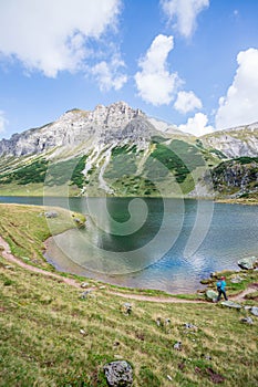 Beautiful and idyllic mountain landscape scenery: Mountain range, lake with clear water and blue cloudy sky