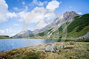 Beautiful and idyllic mountain landscape scenery: Mountain range, lake with clear water and blue cloudy sky