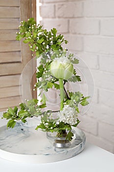 Beautiful ikebana for stylish house decor. Floral composition with fresh tulip flower and blooming branches on white table