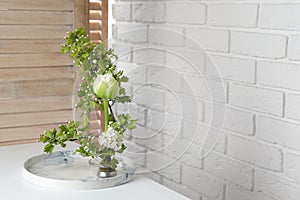 Beautiful ikebana for stylish house decor. Floral composition with fresh tulip flower and blooming branches on white table, space