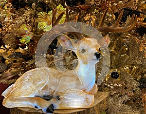 A beautiful illuminated deer in front of christmas tree with golden decorations