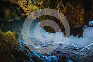 Beautiful illuminated limestone stalactites in Adygeya cave, underground river with reflection of blue light photo