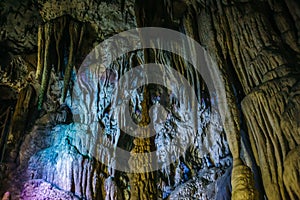 Beautiful illuminated limestone stalactites in Adygeya underground cave, speleology grotto