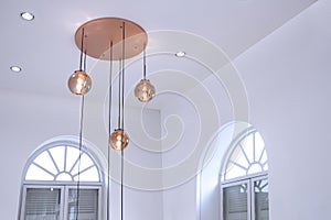 Beautiful illuminated modern ceiling round rose gold glass chandelier with arch wooden windows inside of white living room