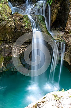 Beautiful image of blurred stream of waterfalls falling over mossy rocks