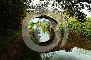 A beautiful image of a bridge over a canal - The reflection is clear in the water