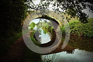 A beautiful image of a bridge over a canal - The reflection is clear in the water