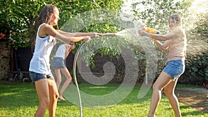 Beautiful image of happy laughing family with children having fun at hot summer day with water guns and garden hose