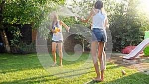 Beautiful image of happy laughing family with children having fun at hot summer day with water guns and garden hose