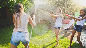 Beautiful image of happy laughing family with children having fun at hot summer day with water guns and garden hose