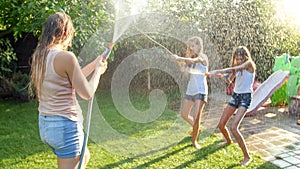 Beautiful image of happy laughing family with children having fun at hot summer day with water guns and garden hose