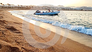 Beautiful image of inflatable motorboat floating on sea waves against beutiful sunset