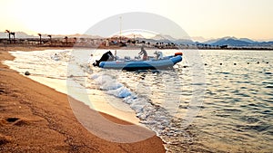 Beautiful image of inflatable motorboat floating on sea waves against beutiful sunset