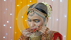 Beautiful Indian bride putting on a nose ring - bridal makeup in Indian wedding