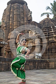 Beautiful indian girl dancer of Indian classical dance Odissi posing in front of Mukteshvara Temple, Bhubaneswar, Odisha, India.Od