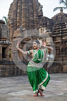 Beautiful indian girl dancer of Indian classical dance Odissi posing in front of Mukteshvara Temple, Bhubaneswar, Odisha, India.Od