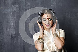 Beautiful Indian woman listening to music on headphones