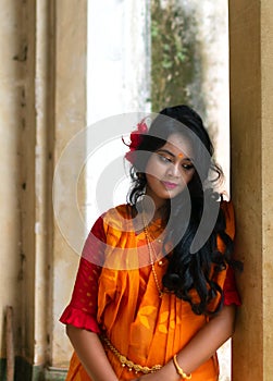 Beautiful indian woman in orange saree standing with a sad mood . concept of broken heart. Valentine`s Day love and faith