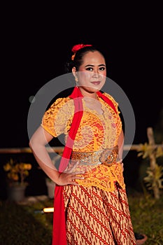 Beautiful Indonesian women wearing an orange traditional dance costume called kebaya when dancing a danced called jaipong