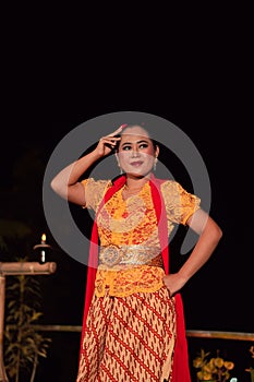 Beautiful Indonesian women wearing an orange traditional dance costume called kebaya when dancing a danced called jaipong