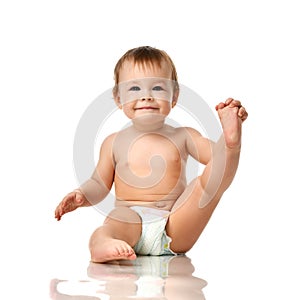 Beautiful infant baby girl toddler sitting in diaper and hold one leg