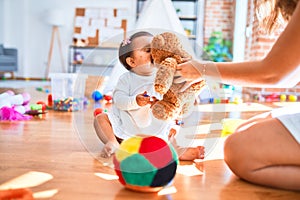 Beautiful infant happy at kindergarten around colorful toys